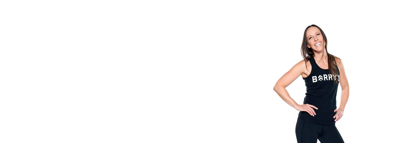 Barry's instructor Angel Chelik wearing black tank posing with hands on hips