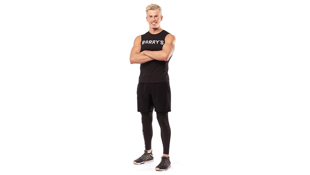 Barry's Bootcamp instructor Brendan Sorichetti standing against a white background with his arms crossed.