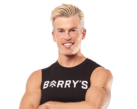 Barry's Bootcamp instructor Brendan Sorichetti standing against a white background with his arms crossed.