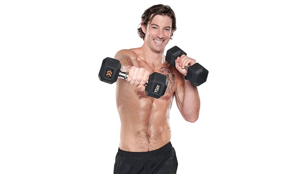barry's instructor Brian Tschida wearing a black tank posing with dumbbells