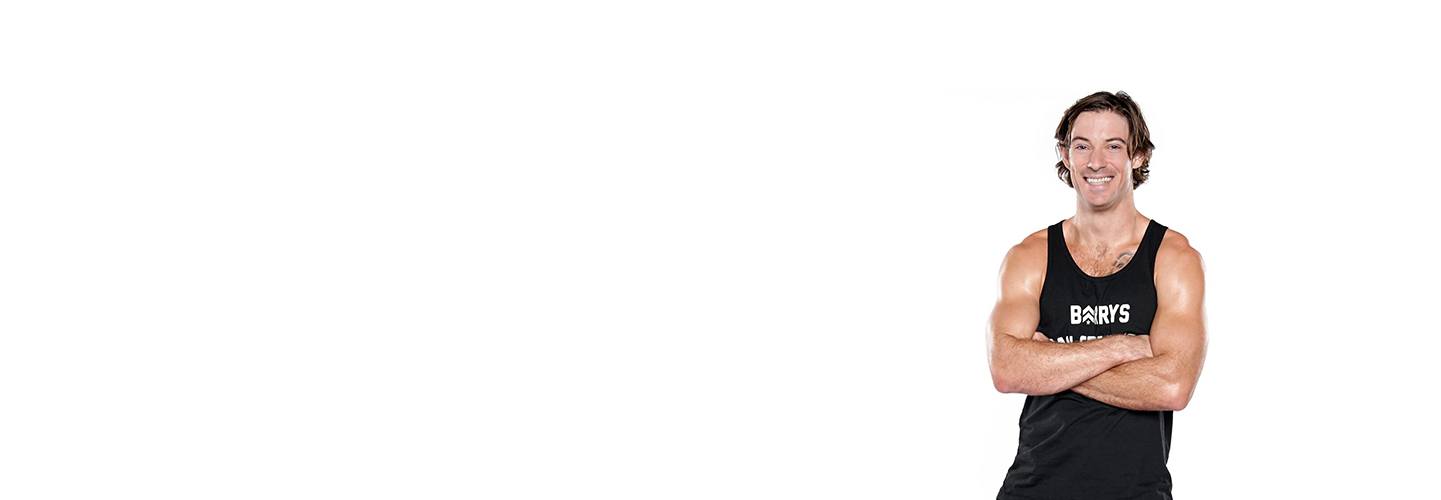 barry's instructor Brian Tschida wearing a black tank posing with arms folded.