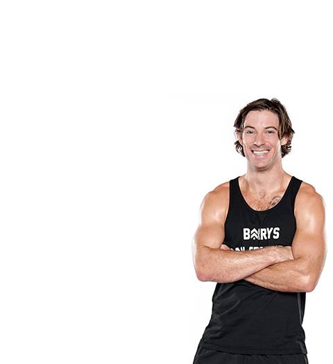 barry's instructor Brian Tschida wearing a black tank posing with arms folded.