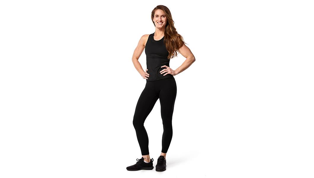 Instructor Candice Peak in black activewear standing with hands on hips on white background