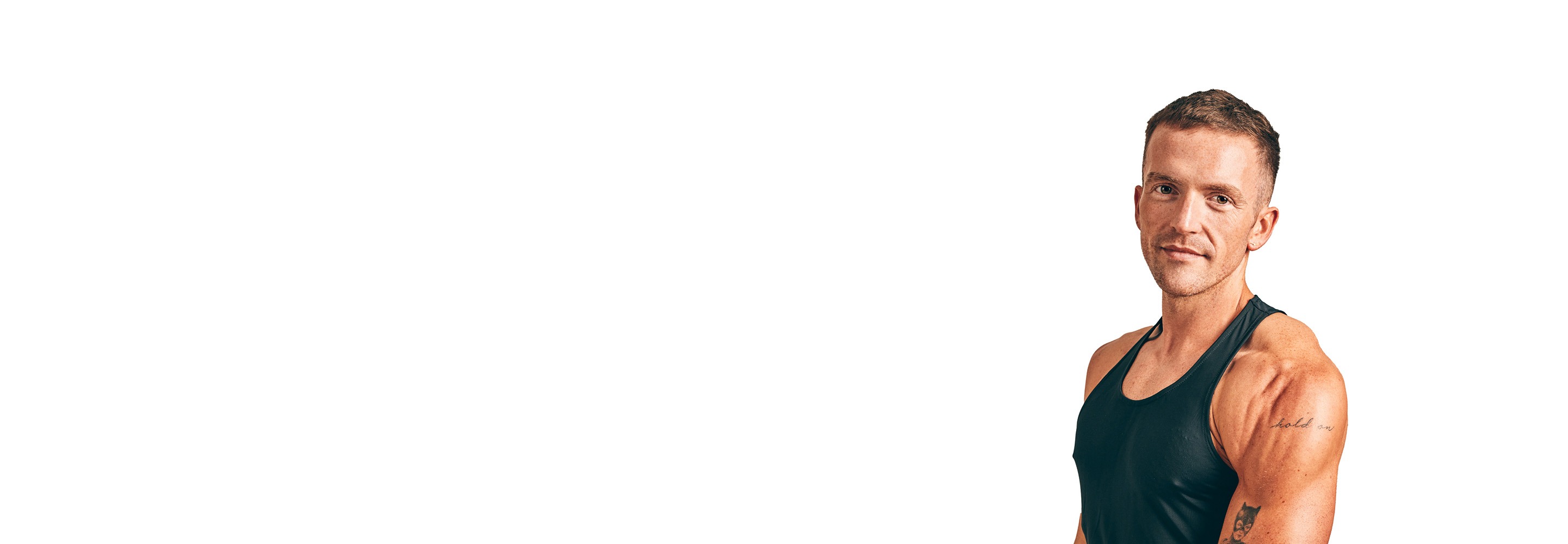 Barry’s instructor wearing a black top standing confidently smiling against a white background