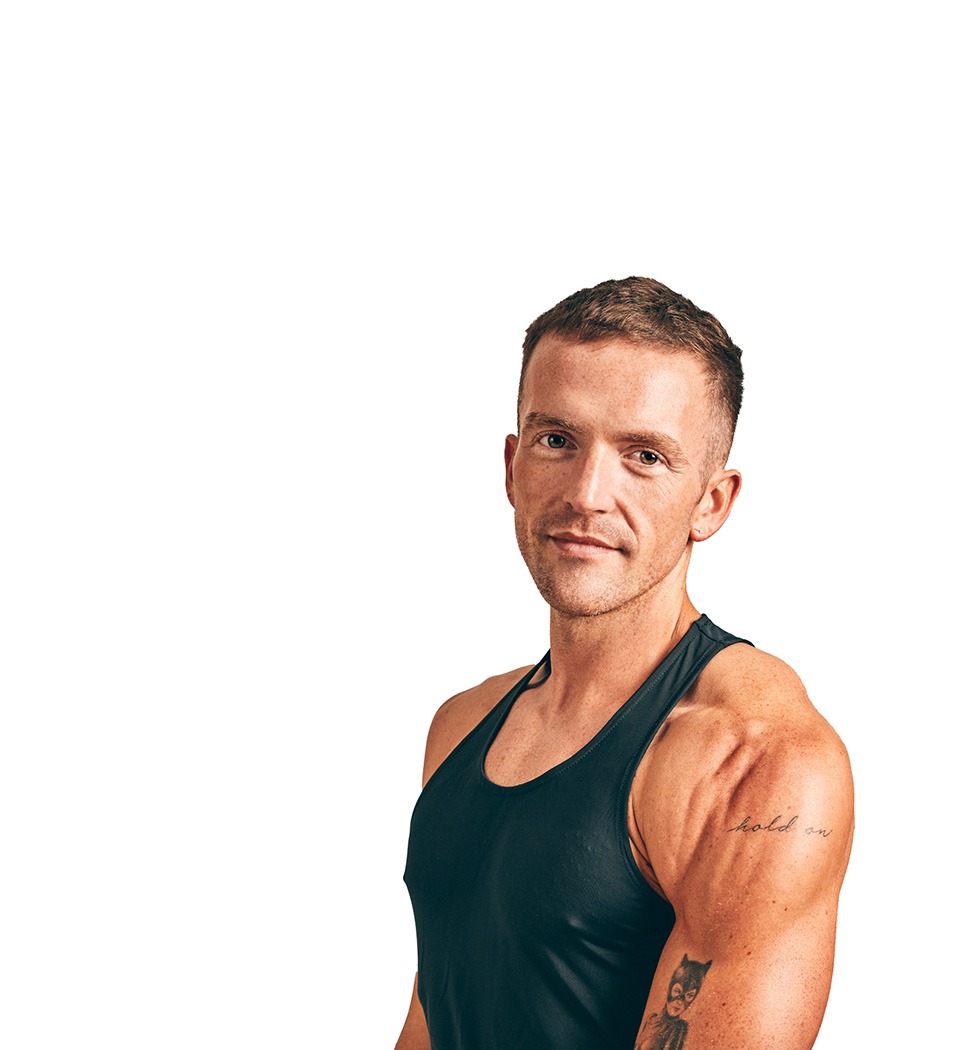 Barry’s instructor wearing a black top standing confidently smiling against a white background