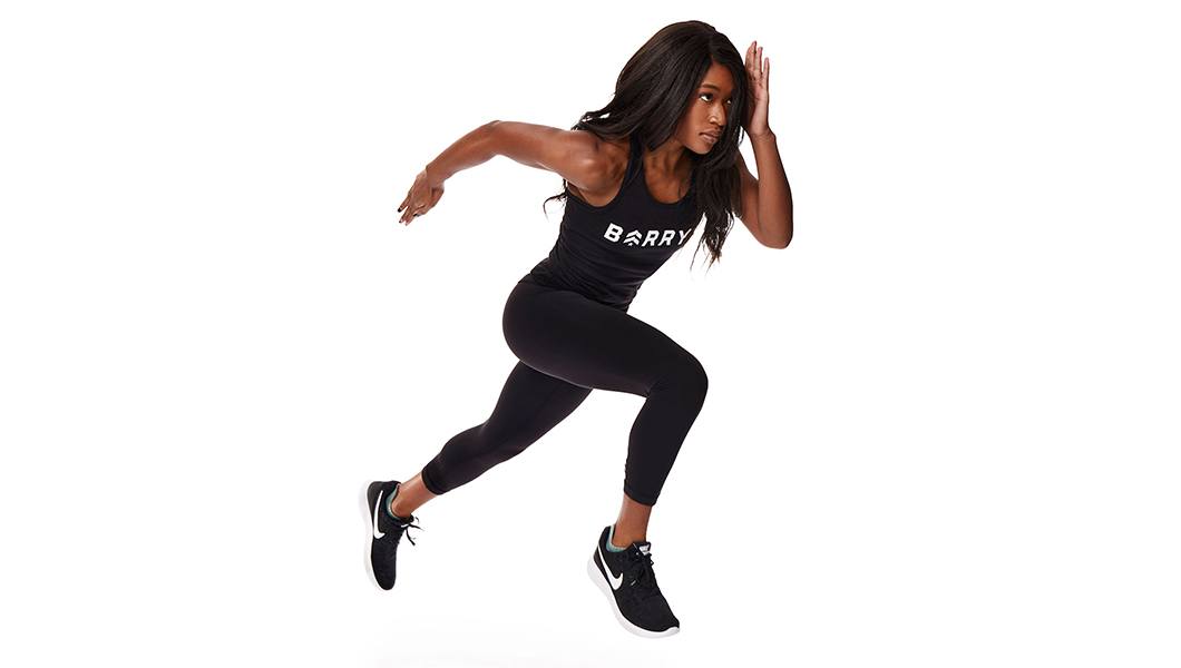 Barry’s instructor wearing a black black workout outfit in a sprint against a white background