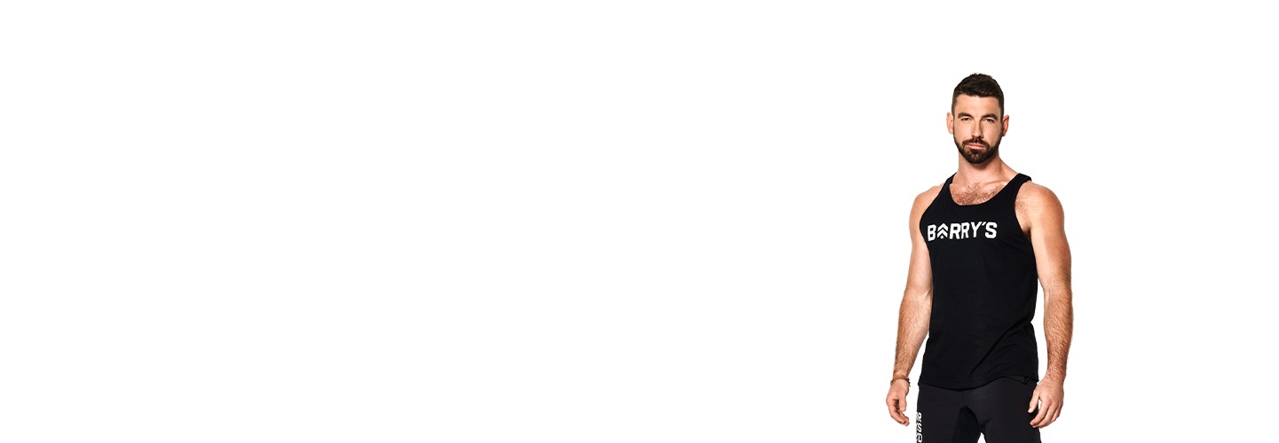 Barry's Bootcamp instructor Cory Gooch standing against a white background wearing a tank top with a Barry's logo.