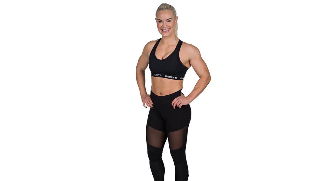 barry's instructor Fam Elgan in black tank posing with hands on hips