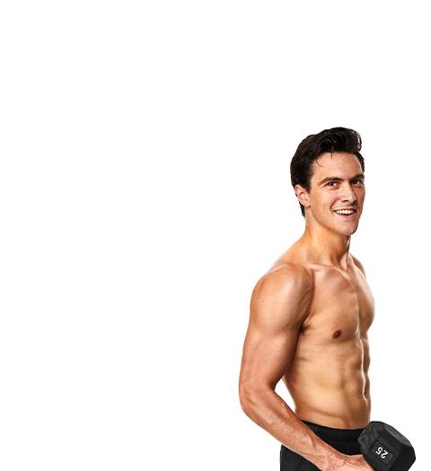Shirtless Barry's Bootcamp instructor Jimmy Nicholas smiling while holding dumbbell on white background