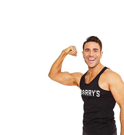 Barry’s instructor wearing a black top standing confidently smiling against a white background