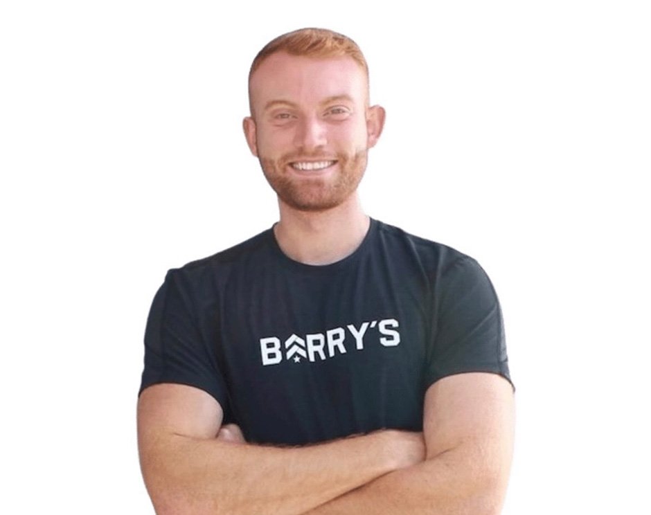 Barry’s instructor wearing a black top standing confidently smiling against a white background