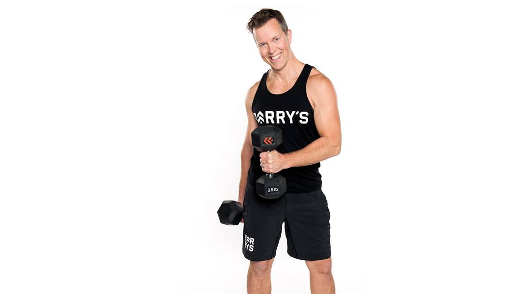 Barry's Instructor Martin George wearing black tank posing with dumbbells
