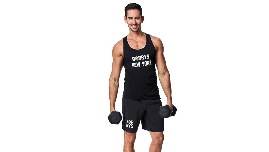 Barry's instructor Matt Griffin wearing black tank posing with dumbbells