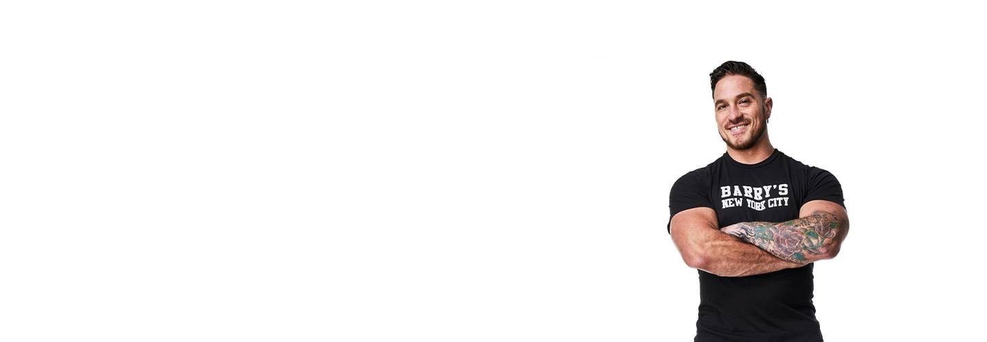 Barry’s instructor wearing a black top standing confidently smiling against a white background