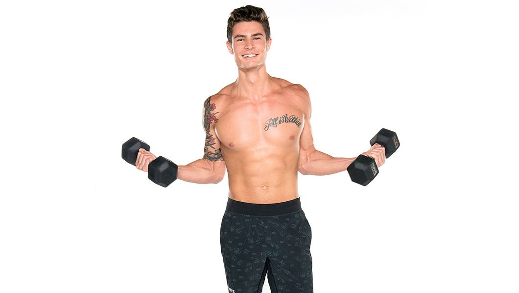 Shirtless Barry's Bootcamp instructor Nolan Zarlin smiling and doing bicep curls with dumbbells in front of white background