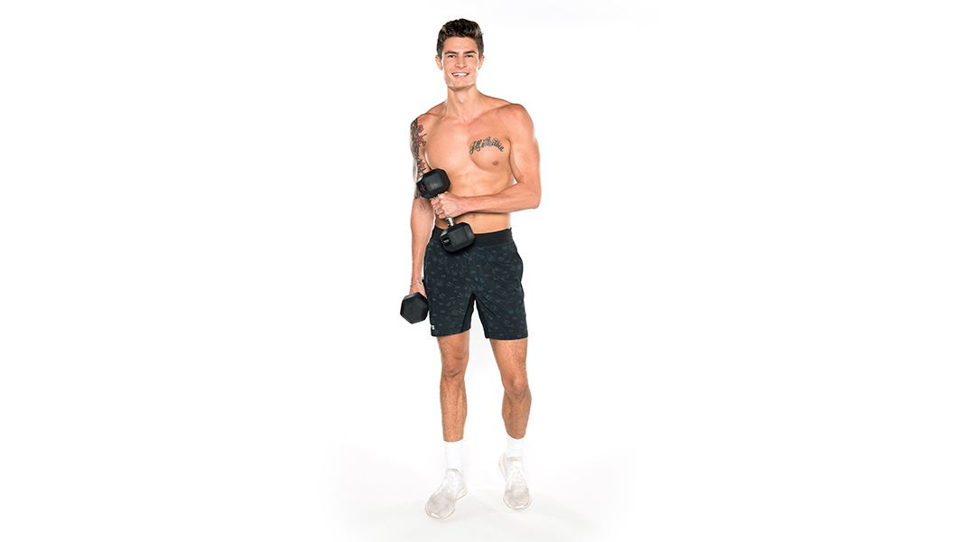 Shirtless Barry's Bootcamp instructor Nolan Zarlin smiling with dumbbells in front of white background