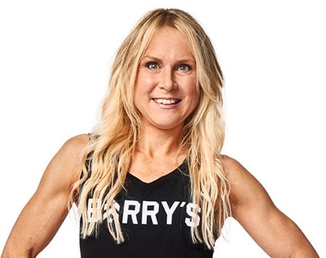 Headshot of instructor Rhonda Hunt in black Barry's Bootcamp tank top smiling with hands on hips on white background