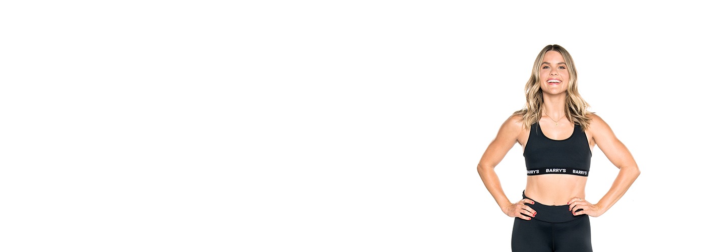 Taryn Brooks wearing a black sports bra with her hands on her hips against a white background.