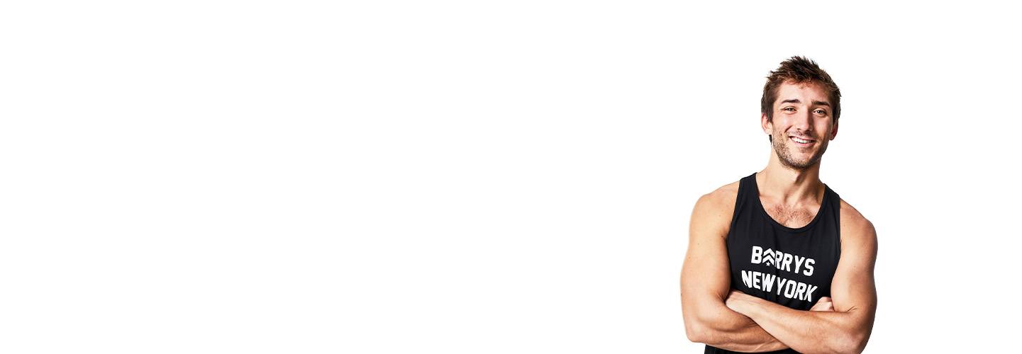 Barry's Bootcamp instructor Taylor Walsh crossing his arms standing in front of a white background.