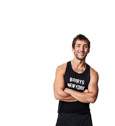 Barry's Bootcamp instructor Taylor Walsh crossing his arms standing in front of a white background.