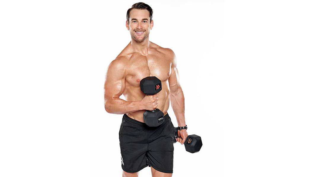 Barry's instructor Tommy Stracke shirtless posing with dumbbells