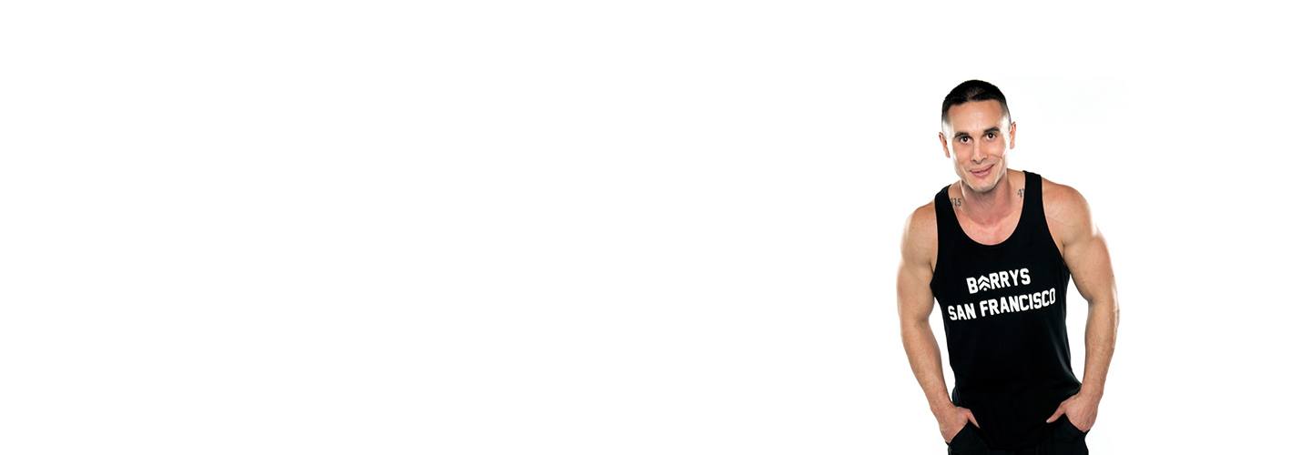 Instructor Vidal Carlin in black Barry's Bootcamp tank top smiling with hands in pocket on white background