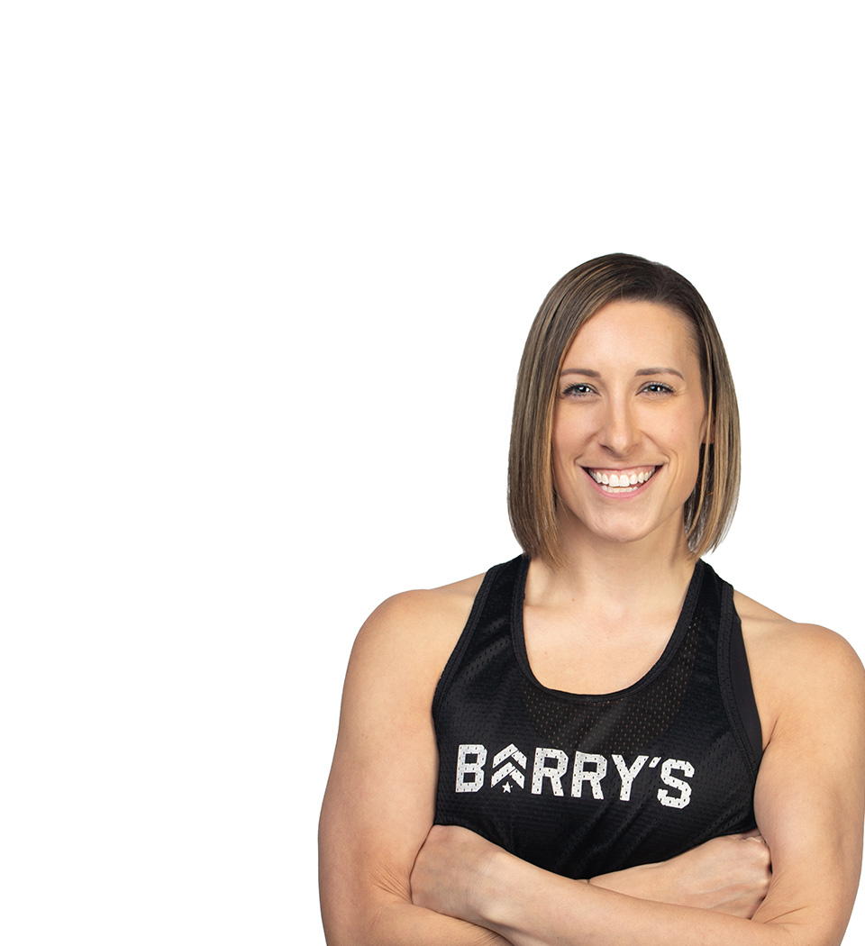 Barry’s instructor wearing a black top standing confidently smiling against a white background