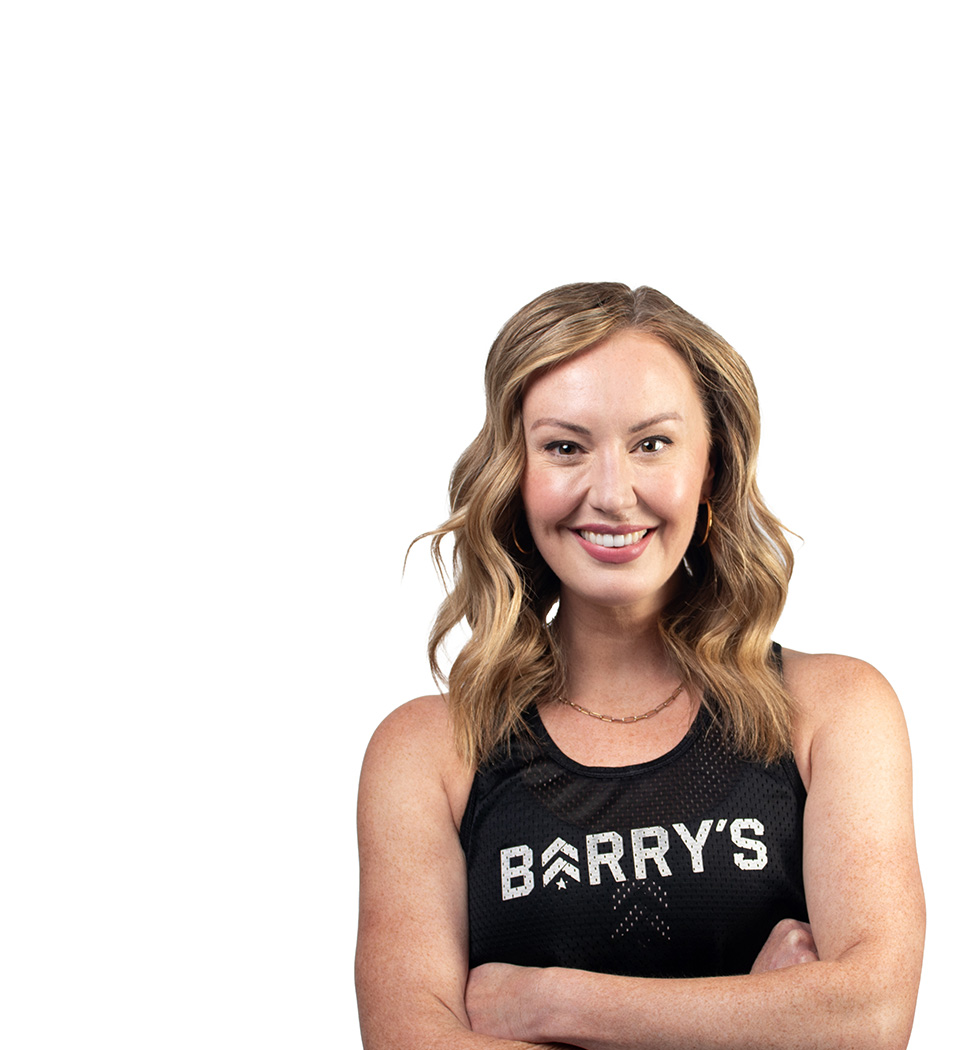 Barry’s instructor wearing a black top standing confidently smiling against a white background