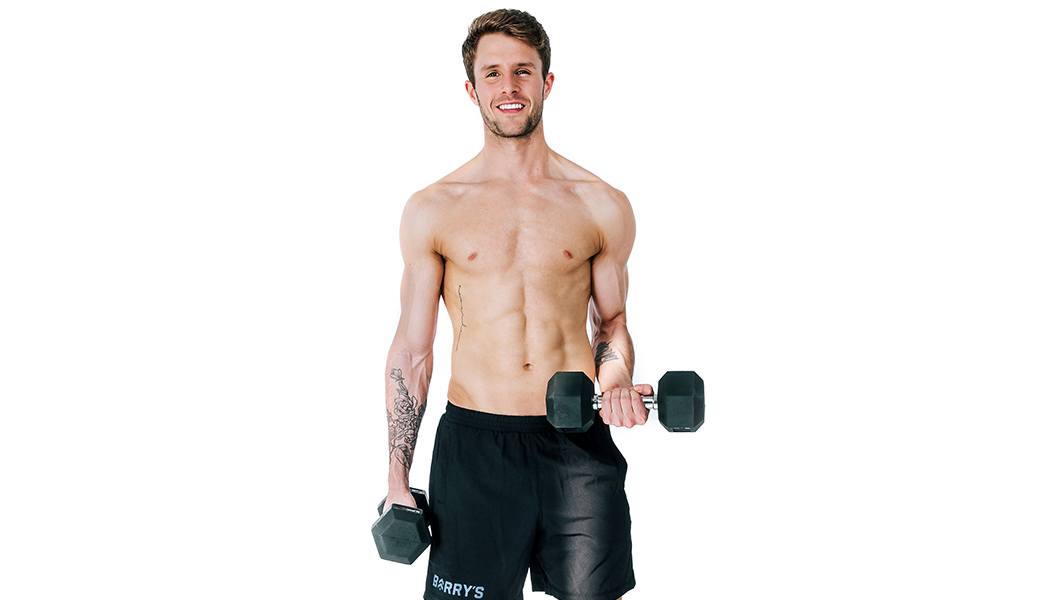 Shirtless Barry's Bootcamp instructor Evan Arbour smiling while doing bicep curl with dumbbell on white background