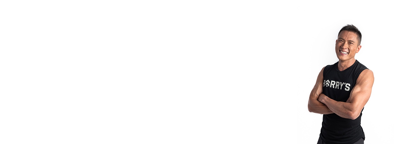 Instructor Ian Chan on white background smiling with crossed arms while wearing Barry's Bootcamp tank