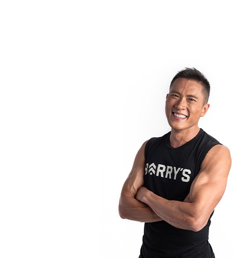 Instructor Ian Chan on white background smiling with crossed arms while wearing Barry's Bootcamp tank
