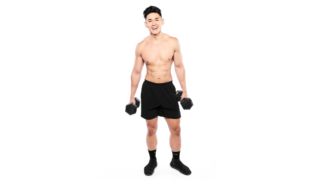 Barry’s instructor shirtless standing confidently smiling against a white background holding weights