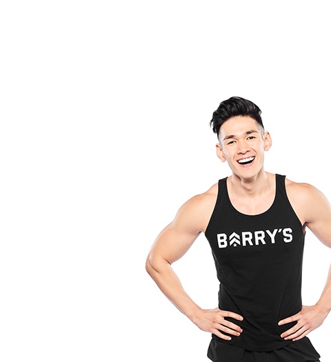 Barry’s instructor wearing a black top standing confidently smiling against a white background