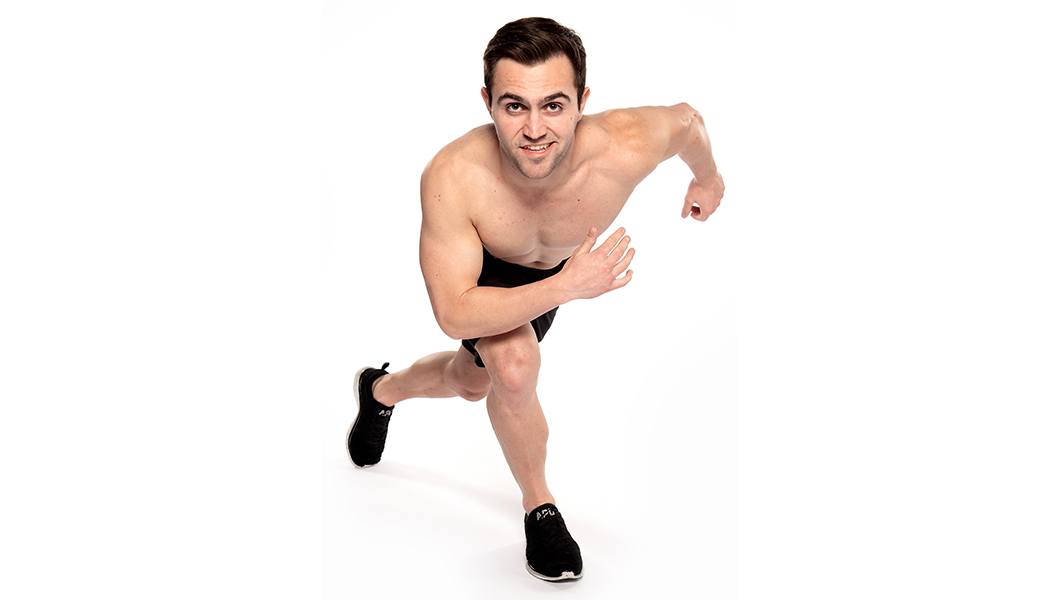 Headshot of Barry's Bootcamp instructor Kael Williams shirtless doing a side ski exercise against a white background.
