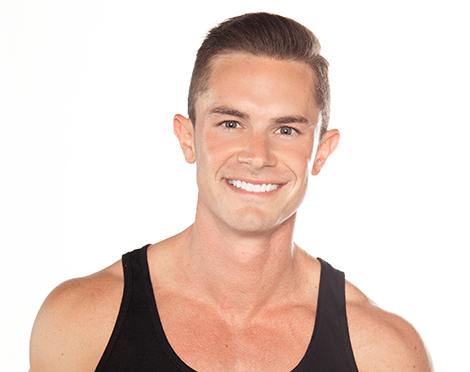 Barry's instructor standing confidently wearing a black tank top against a white background, ready for the next workout challenge.