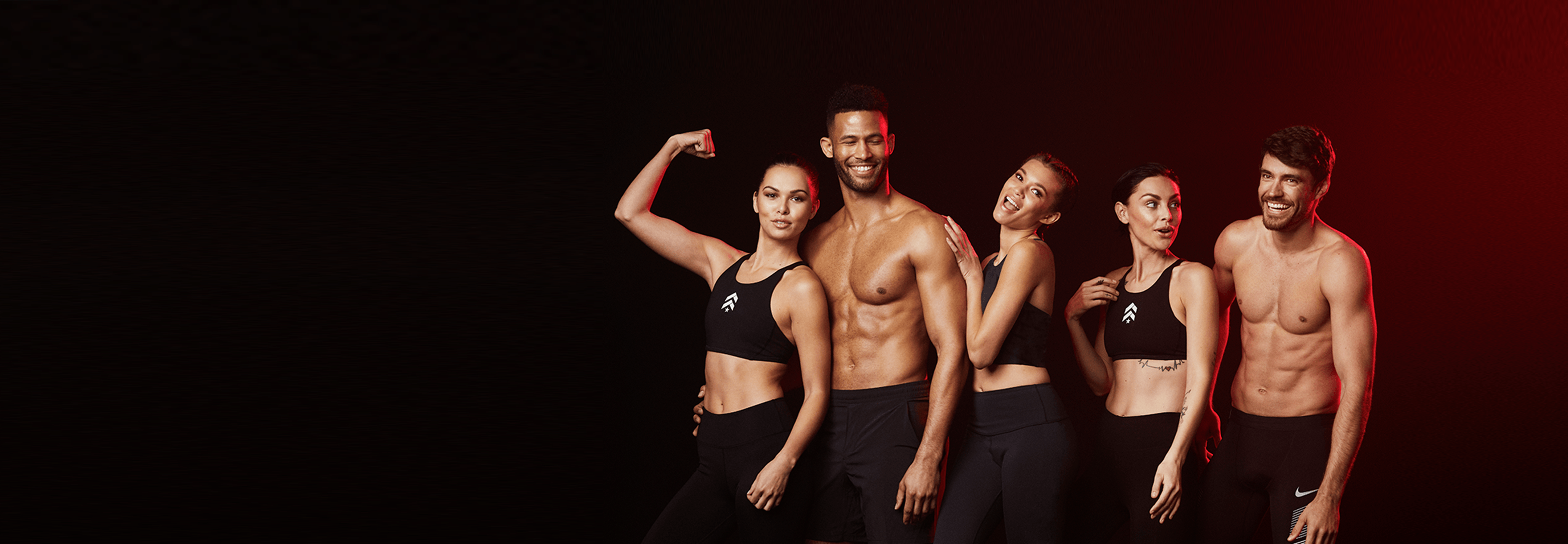Group of female and male Barry's Bootcamp instructors flexing and smiling on black background
