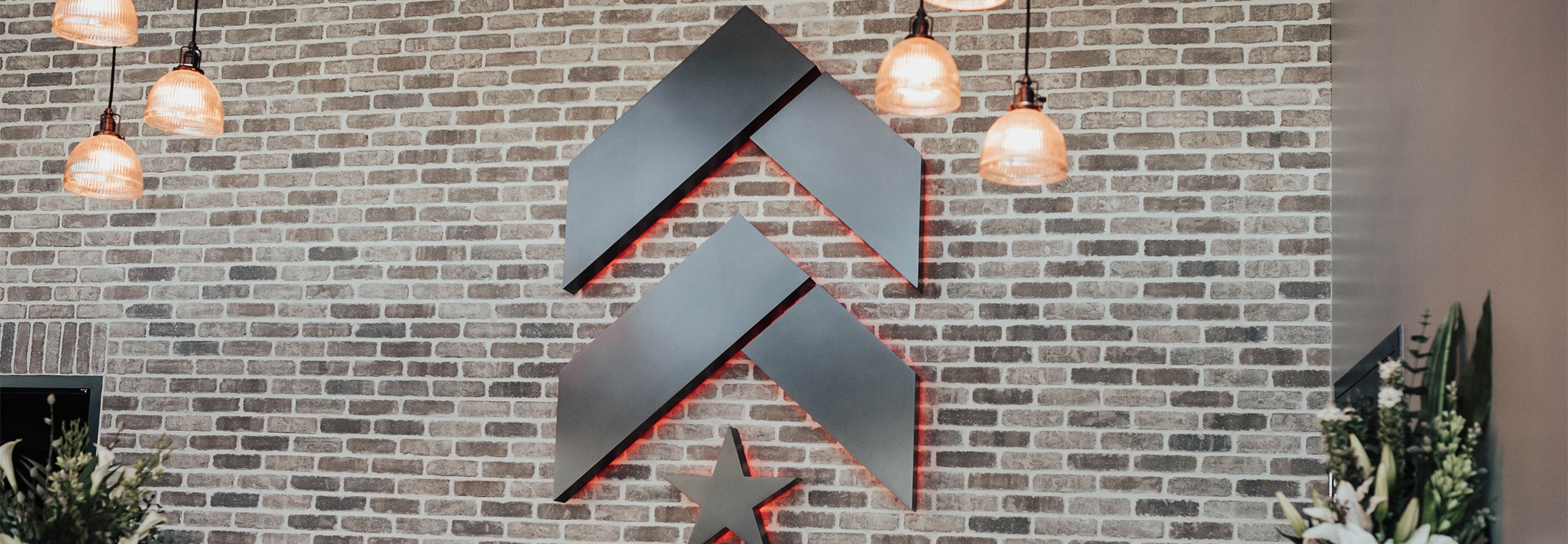 Slate Barry's Bootcamp upward arrows and star logo on grey brick wall in Burlingame studio reception area