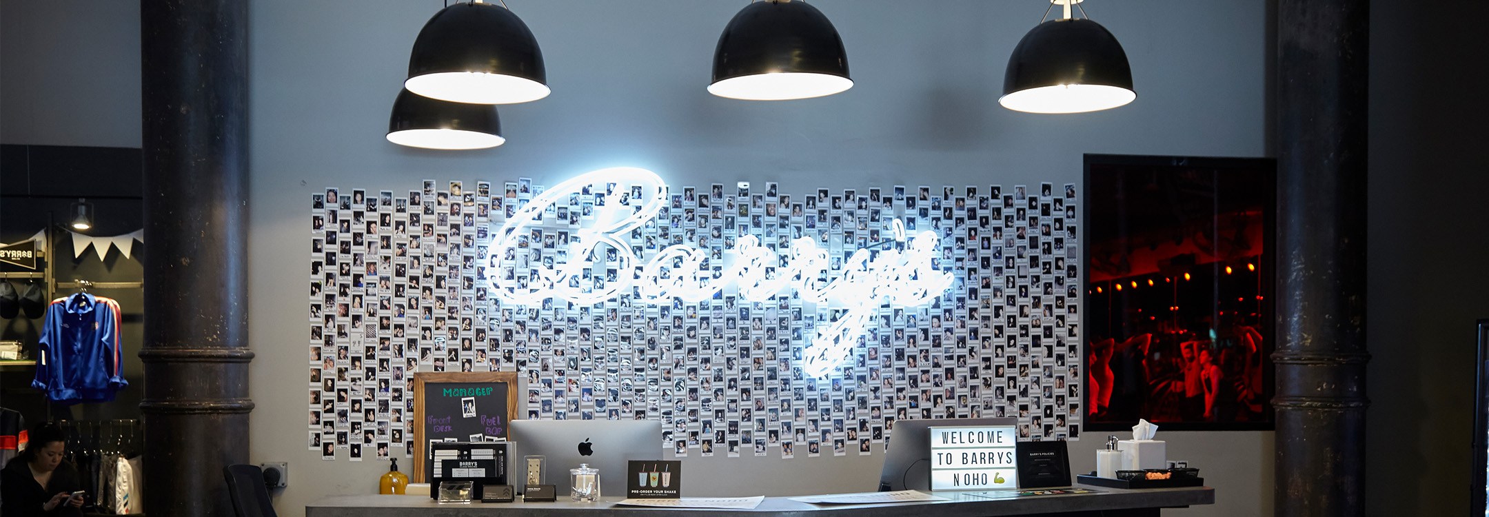 Cursive neon Barry's sign on wall behind reception desk at NoHo studio location