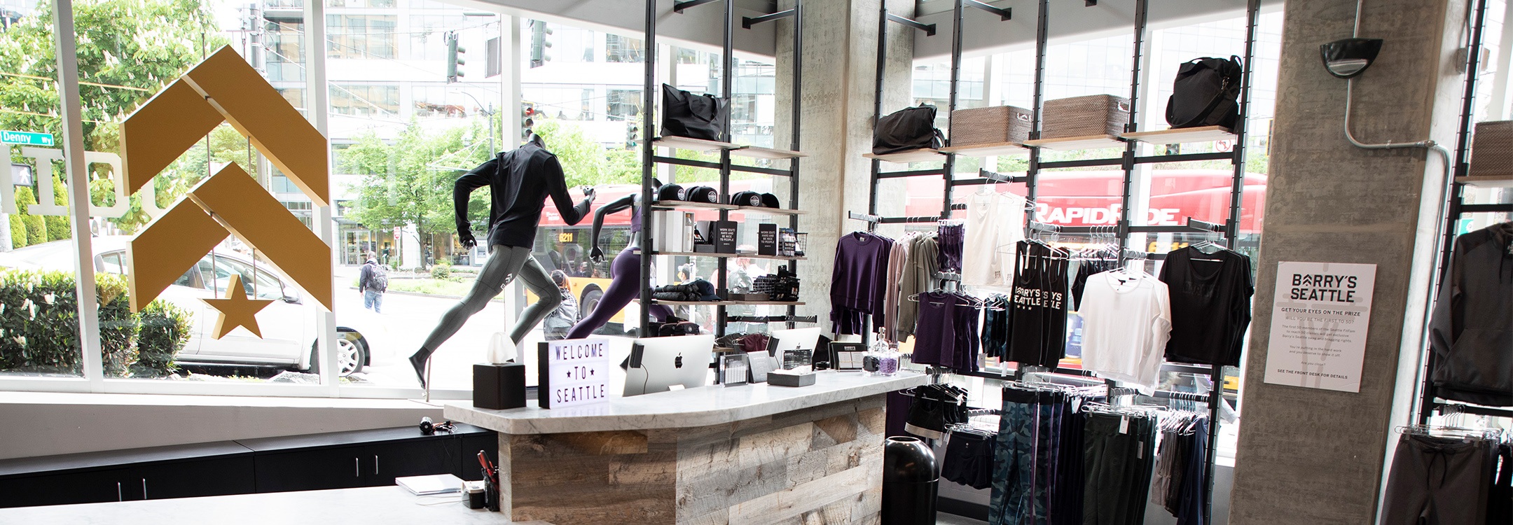 Inside of Barry's Bootcamp Seattle Studio front desk area with Barry's logo in gold on glass windows