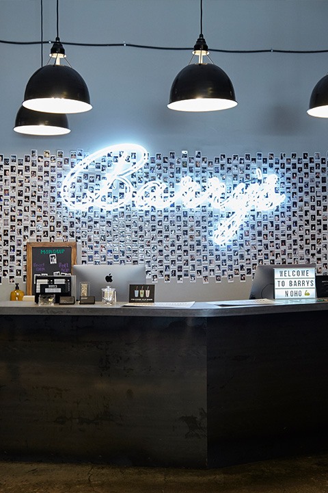 Cursive neon Barry's sign on wall behind reception desk at NoHo studio location