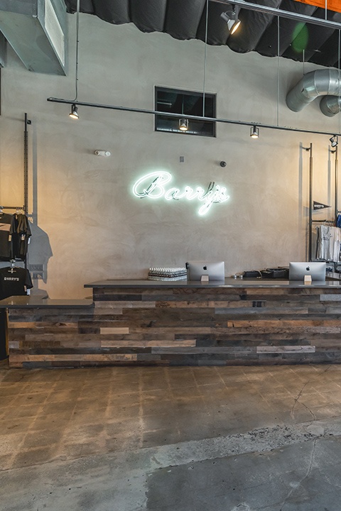 Cursive neon Barry's sign on wall behind reception area at Venice studio location