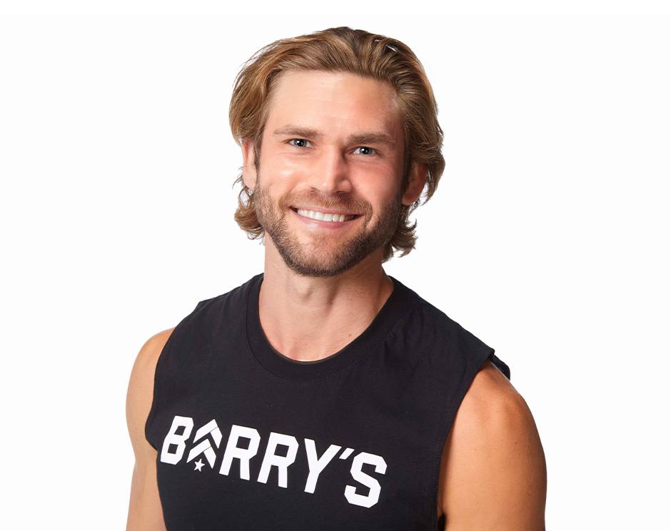 Barry’s instructor wearing a black top standing confidently smiling against a white background