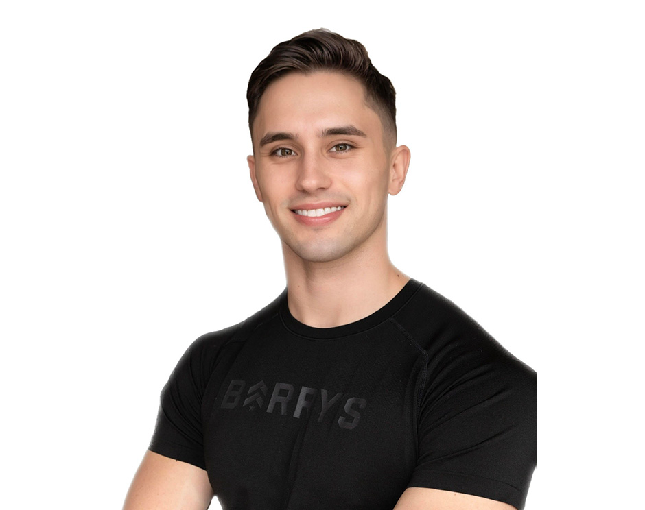 Barry’s instructor wearing a black top standing confidently smiling against a white background