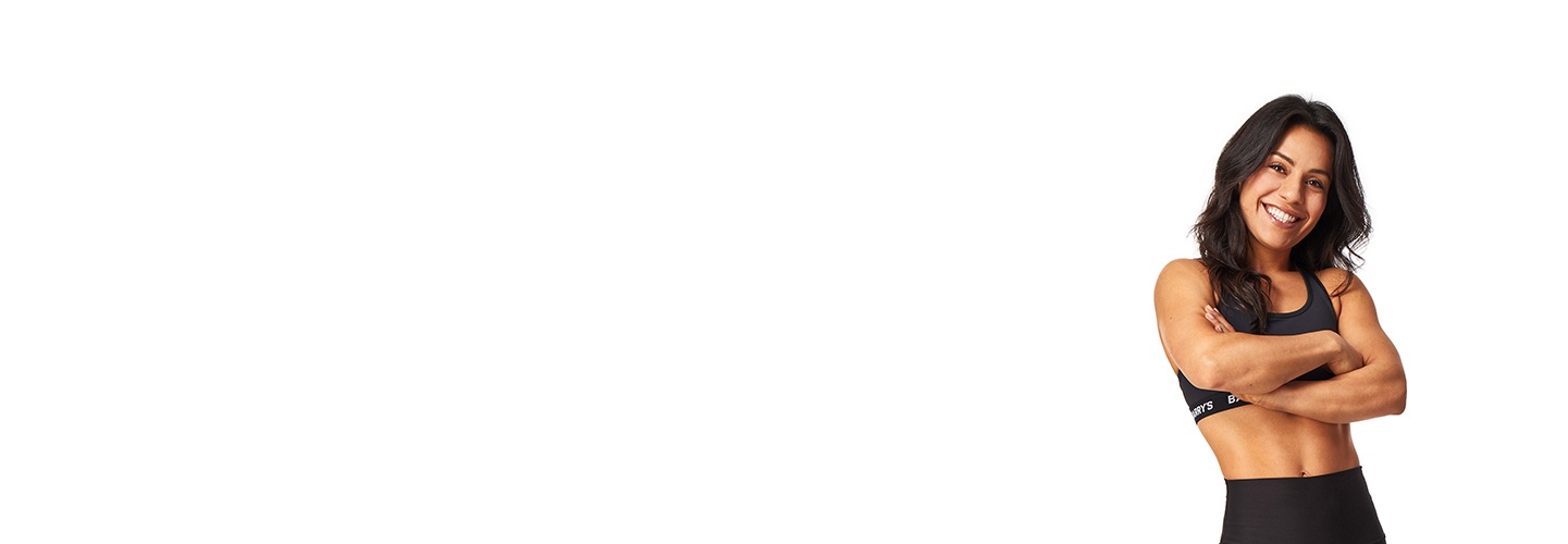 Barry’s instructor wearing a black top standing confidently smiling against a white background