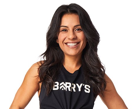 Barry’s instructor wearing a black top standing confidently smiling against a white background