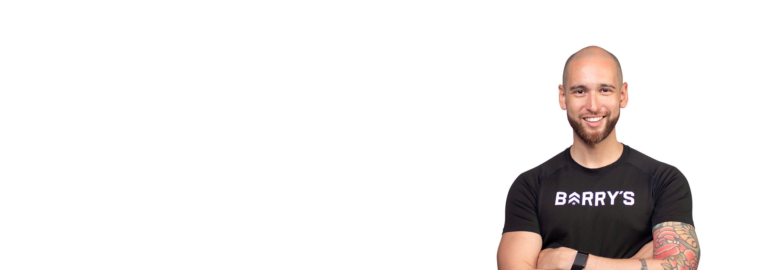 Barry’s instructor wearing a black top standing confidently smiling against a white background