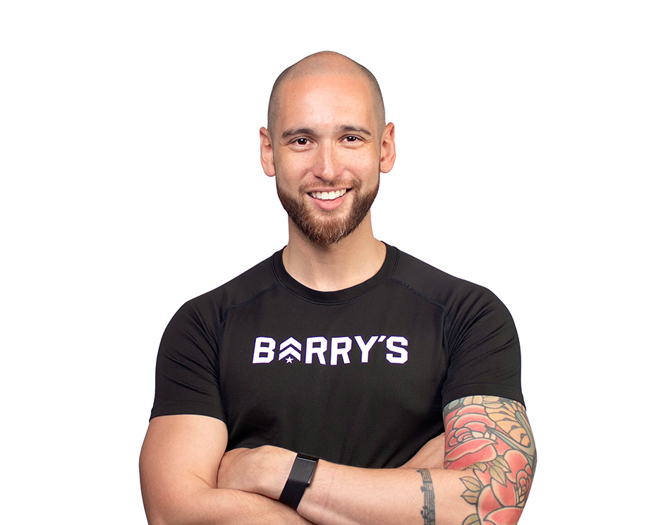 Barry’s instructor wearing a black top standing confidently smiling against a white background