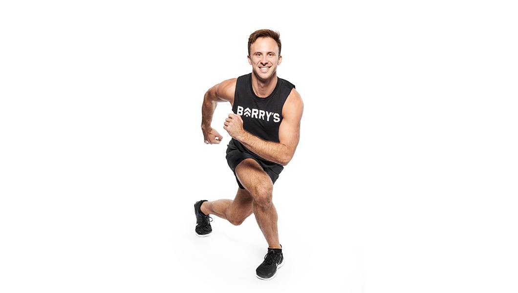 Barry's instructor wearing black shorts and a tank top in a running lunge against a white background.