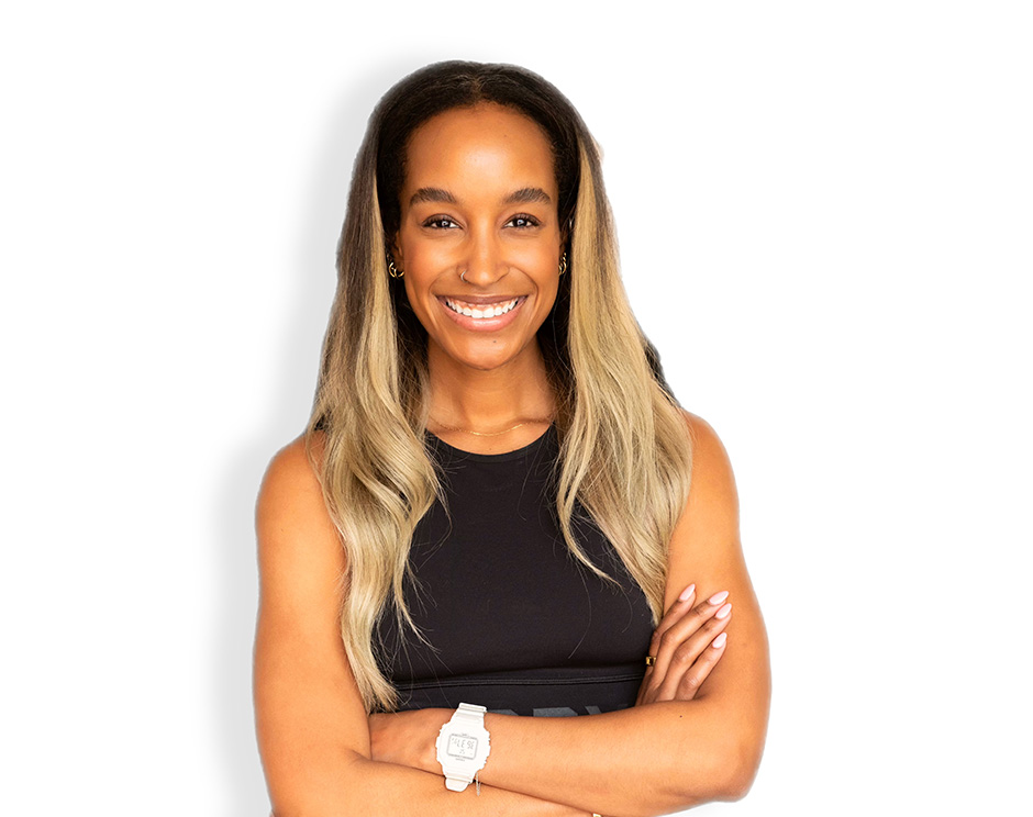 Barry’s instructor wearing a black top standing confidently smiling against a white background