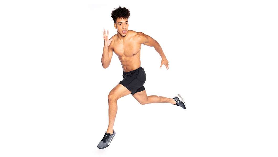 Barry's instructor shirtless with black shorts in a running jump position against a white background